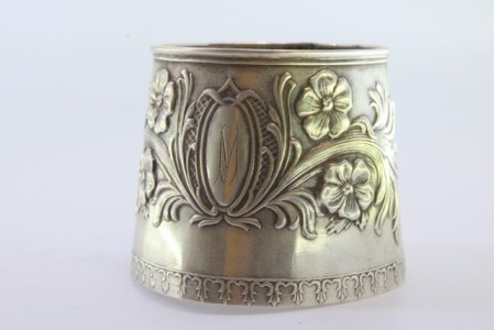 Argola de guardanapo em prata em forma de punho e relevada com motivos florais envolvendo cartela para monograma.